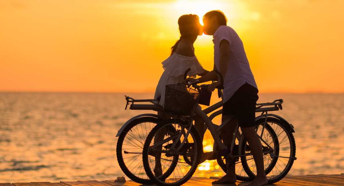 Couple Kissing Over Two Bicycles At Sunset - Date Ideas Canada