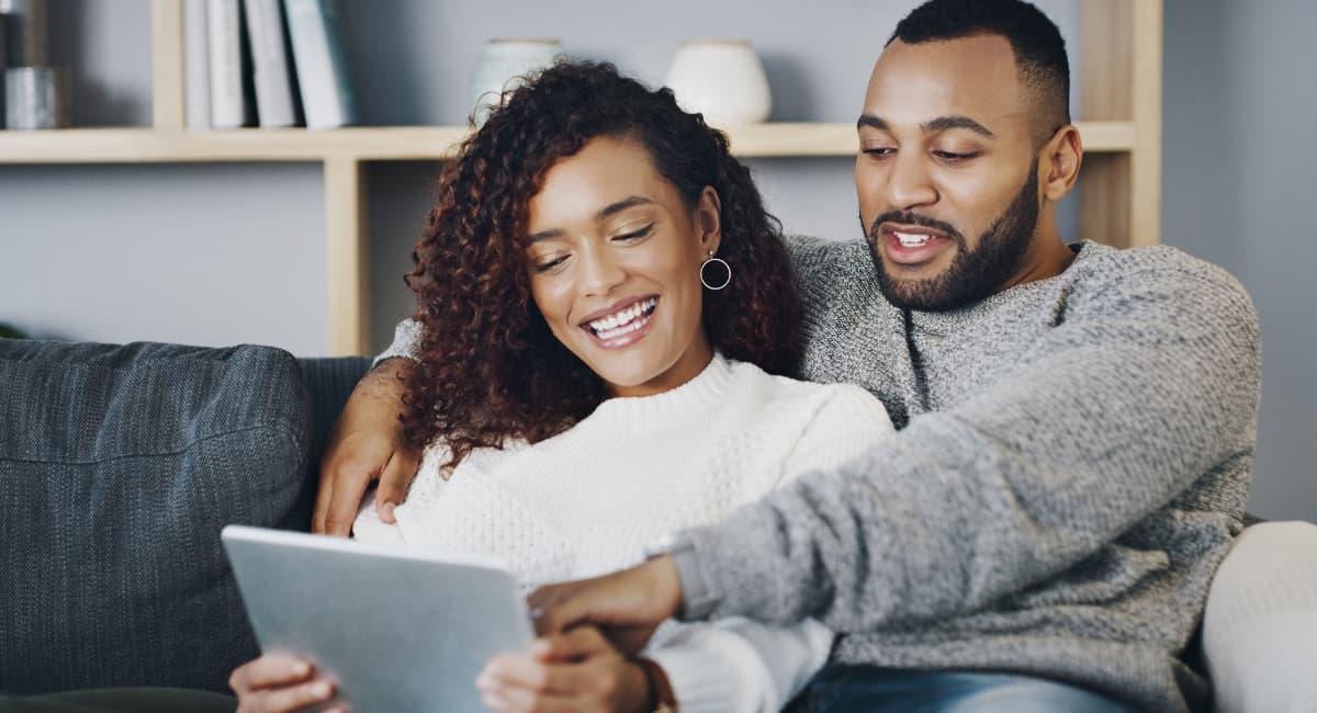 Man with Arms Around Woman on Couch with Laptop - Date Ideas Canada
