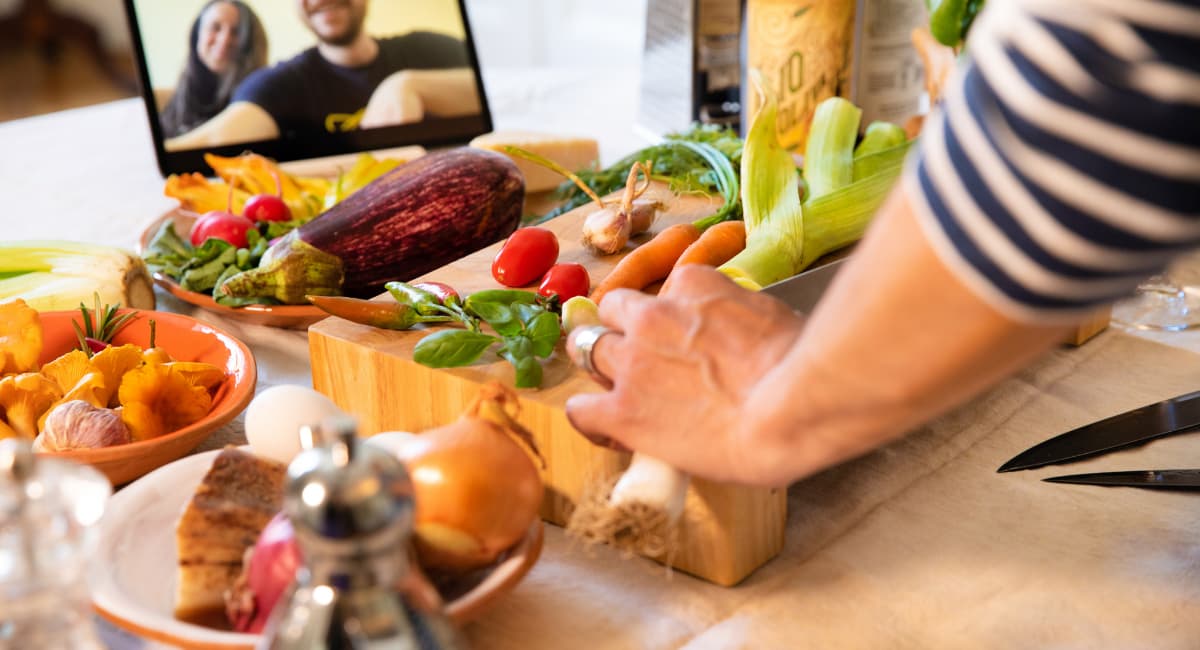 Woman Cooking in Front of Couple Watching Her on Laptop Screen